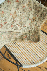 Detail of Oushak rug: floral vinery, ivory, peach, sea foam green, and exposed foundation.