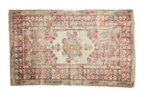 Ivory vintage Anatolian rug with elongated red diamond medallion, floral borders, and soft patina.
