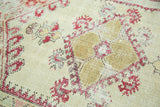 Worn vintage Anatolian rug detail with ivory field, cherry red floral motifs, and exposed foundation.