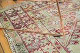 Vintage Anatolian rug detail with worn pile, cherry red, ivory, and pale green geometric motifs.