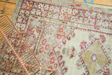 Detail of Anatolian rug: cherry red splayed floral cross-sections, pale seafoam field, and visible wear.