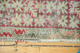 Vintage Anatolian rug border with cherry red, ivory, pale green meandering vine, tattered fringe.