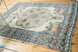 Antique Kerman rug corner spandrel, delicate floral vines in beige, blue, cochineal, worn edges.