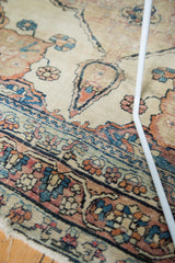 Worn border detail of the antique Kerman rug, showing exposed foundation and faded floral motifs.