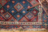 Rich gem-tone borders and tribal geometric motifs on an antique Jaff Kurd rug corner.
