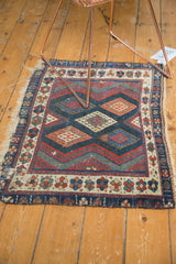 Antique Jaff Kurd rug's unusual geometric design, floral border, and tattered bottom edge.