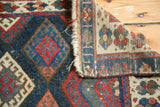 Hand-knotted pile with deep red and indigo diamond motifs meeting the intricately woven foundation of an antique Jaff Kurd rug.