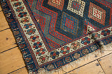Antique Jaff Kurd rug corner with ivory border featuring stylized red and blue geometric motifs.