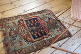 Antique Anatolian rug, displaying cobalt blue and cherry red village motifs with aged fringed edges.