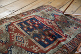 Antique Anatolian rug, displaying worn pile, tattered ends, and geometric blue, red, beige motifs.