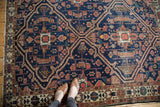 Antique Malayer rug's indigo double medallion, rectilinear pattern, and time-softened edge patina.