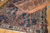 Antique Malayer rug corner with indigo, terra cotta rectilinear patterns and worn fringe.