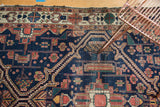 Intricate serrated rectilinear motifs in indigo blue and terra cotta on an antique Malayer rug.