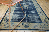 Visibly worn cobalt blue field of antique Peking rug with ivory border and fruit vinery.