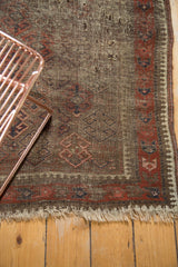 Geometric rams horn pattern and rustic tones on a Vintage Belouch rug corner with tattered fringe.