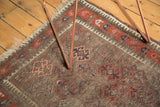 Vintage Belouch rug corner with geometric rams horn motifs and woven brown, red, blue texture.