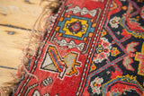 Antique Malayer rug detail: red geometric border, dark field motifs, and tattered fringe.