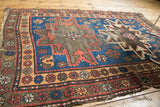 Rectilinear motifs on indigo blue field of vintage Caucasian rug, with tattered edges.