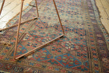 Antique Kurd rug's distressed texture, geometric lattice, and unique meandering leaf border.