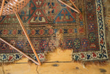 Tattered edge and visible holes with geometric patterns on an antique Kurdish rug.
