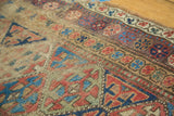 Intricate geometric and meandering leaf borders with distressed texture on an antique Kurd rug.