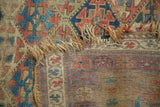 Close-up of hard distress, tattered edge, and geometric pattern on antique Kurd rug.