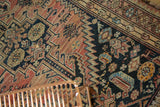 Faded blush, navy serrated geometric patterns, wear, and hole on antique Malayer rug.