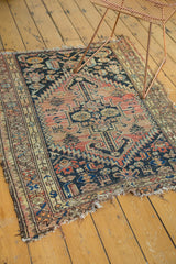 Antique Malayer rug's bottom right corner, displaying tattered edges and worn geometric motifs.