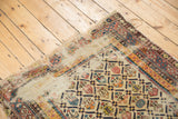 Worn corner of an antique Caucasian Shirvan rug showing geometric lattice and exposed foundation.