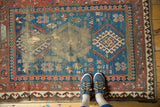 Antique Caucasian rug detail: indigo blue field with geometric patterns and exposed foundation from wear.