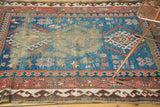 Antique Caucasian rug: indigo field, angular geometric designs, and exposed foundation.