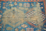 Antique Caucasian rug with three large holed areas, showing indigo and terra cotta.
