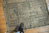 Upper-left corner of antique Caucasian rug, geometric navy blue on sand, with frayed edge.