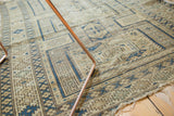 Geometric patterns in navy blue and aged ivory on a worn Antique Caucasian rug edge.