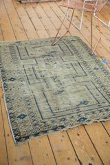 Antique Caucasian rug's lower corner with visible tattered fringe and navy geometric borders.