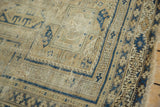 Tattered corner of an antique Caucasian geometric rug, revealing navy blue guls and sand tones.
