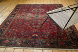 Corner of vintage Lilihan rug features cherry red floral field, navy border, exposed foundation.