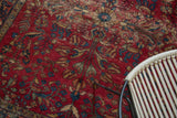 Ornate vinery, tendrils, and floral cross-sections on cherry red vintage Lilihan rug.