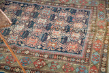 Antique Shirvan rug's geometric crab motif in indigo, madder red, and sky blue, showing wear.