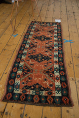 Hand-knotted vintage Afghan rug corner, navy, green, and brick red geometric border.