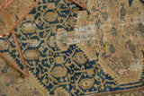 Visible holes, tatter, and mending on the vintage Tajabad rug's teal blue and beige pattern.