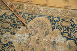 Close-up of vintage Tajabad rug's storied wear, mending, and faded teal blue patterns.