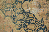 Serrated dark blue motifs on a worn beige ground of a vintage Tajabad rug with visible loss.