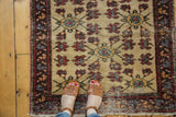 Vintage Turkish rug with antique ivory field, wine red floral trellis, and short fringe.