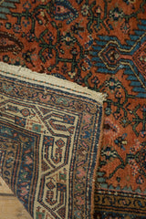 Folded vintage Tajabad rug revealing blush, sky blue pile and woven, geometric patterned reverse.