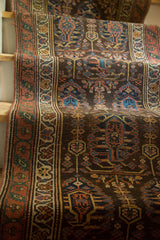 Richly patterned border and field of charcoal, madder red, teal blue on antique Persian runner.