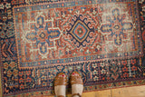 Karaja rug's triple medallion and serrated leaves, brick red and navy palette, showing wear.