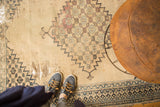 Close-up of extensive tatter and exposed foundation on the beige antique Persian Doroksh rug.