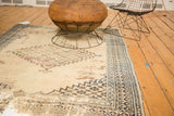 Antique Doroksh rug corner with navy geometric border and faded ivory field showing wear.