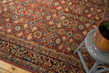 Cherry red field with repeating floral pomegranate motif and navy border on vintage Mahal rug.